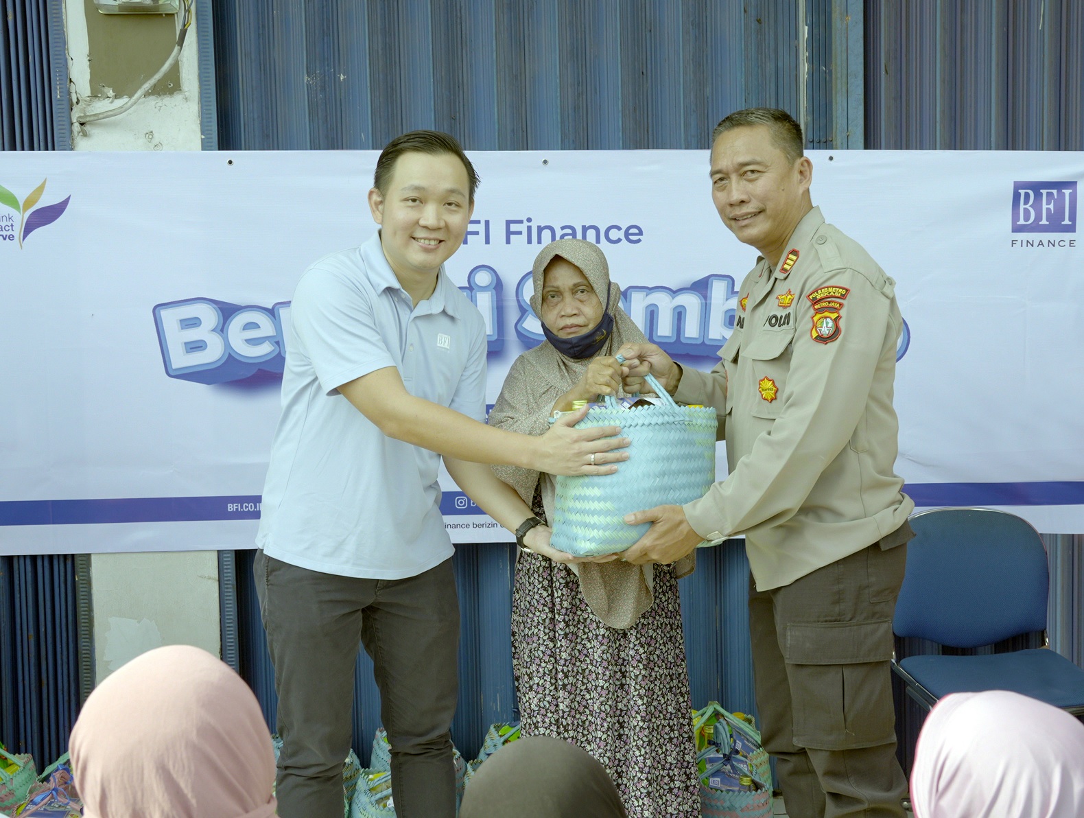 A Tambun resident receives grocery package from Benny Hermawan, Area Manager Asset Management of BFI Finance Jakarta (left), accompanied by Deputy Chief of Tambun Subdistrict Police Station (Wakapolsek Tambun), AKP Suhardi 